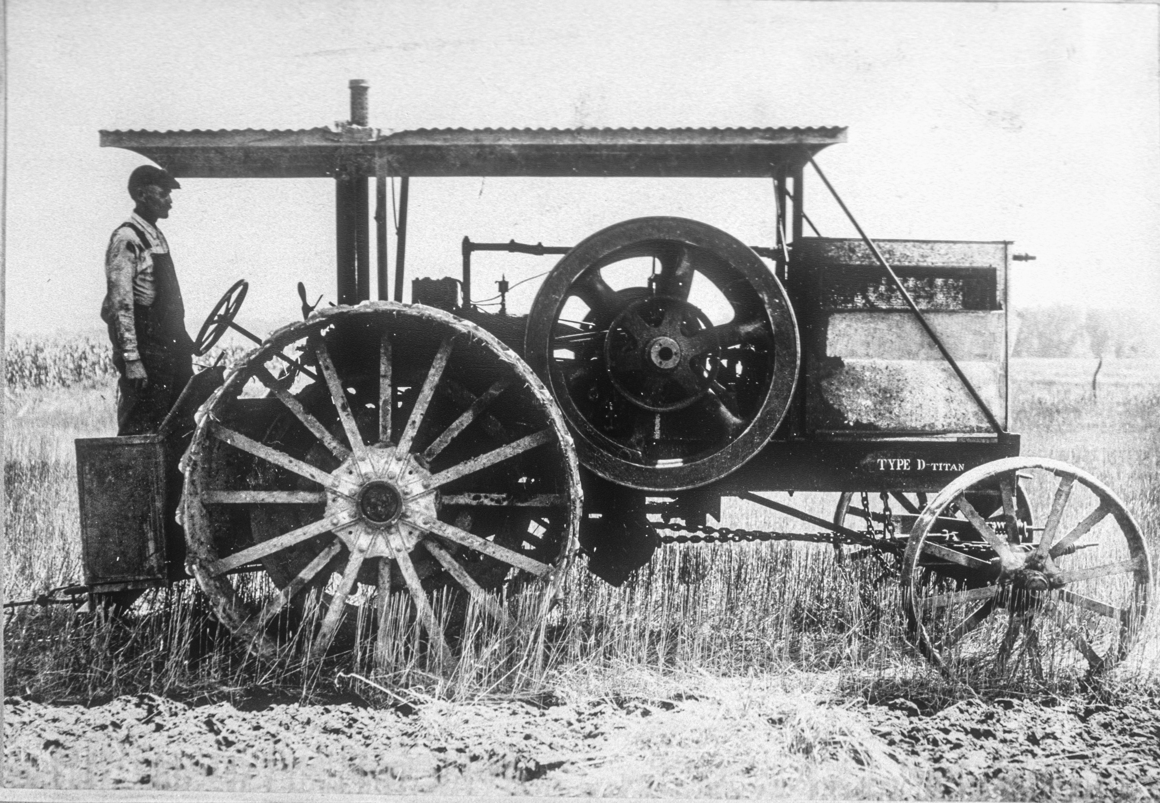 Historic photo of Titan Type D in field with men on it. 