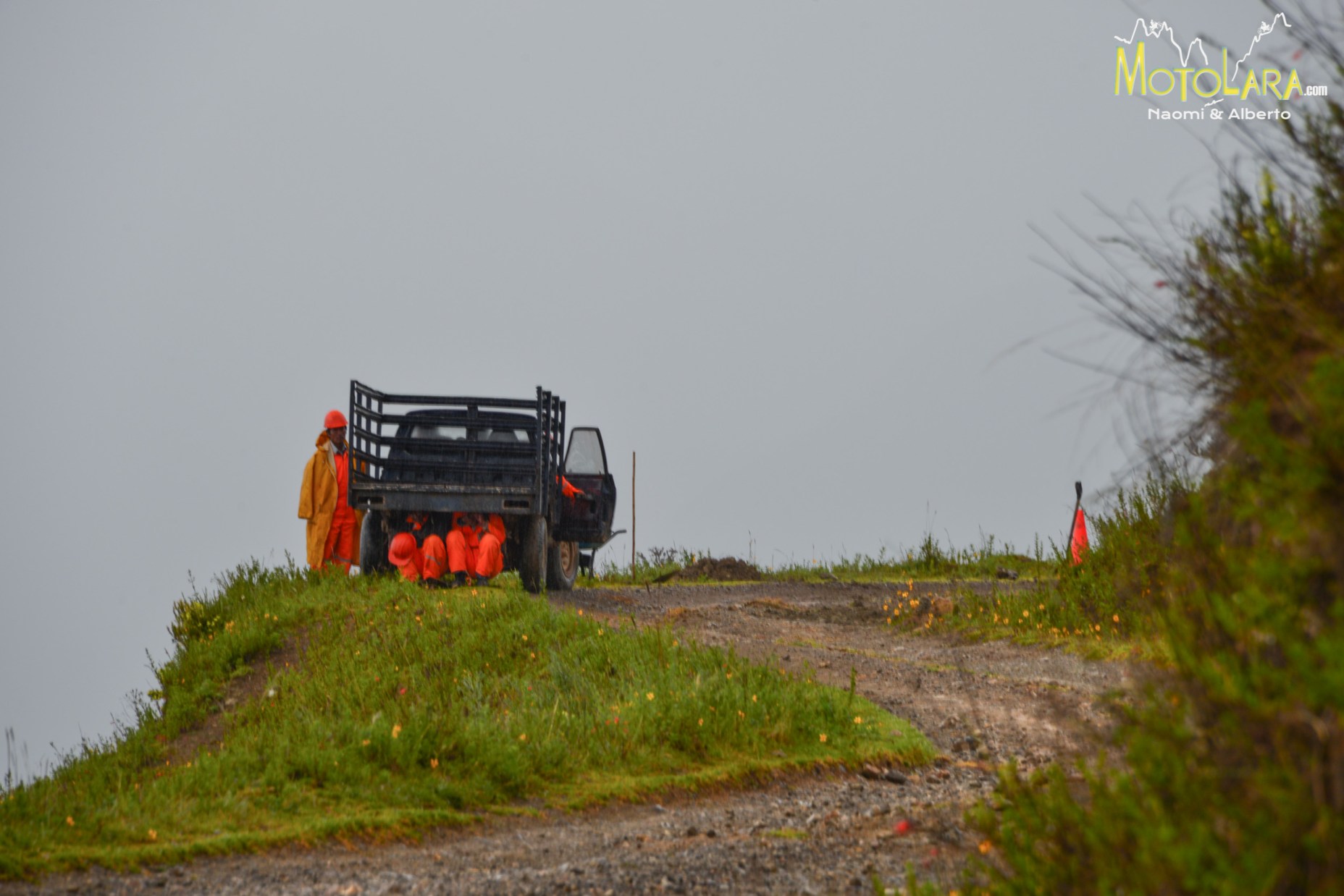 Construction crew hiding from the rain under their truck